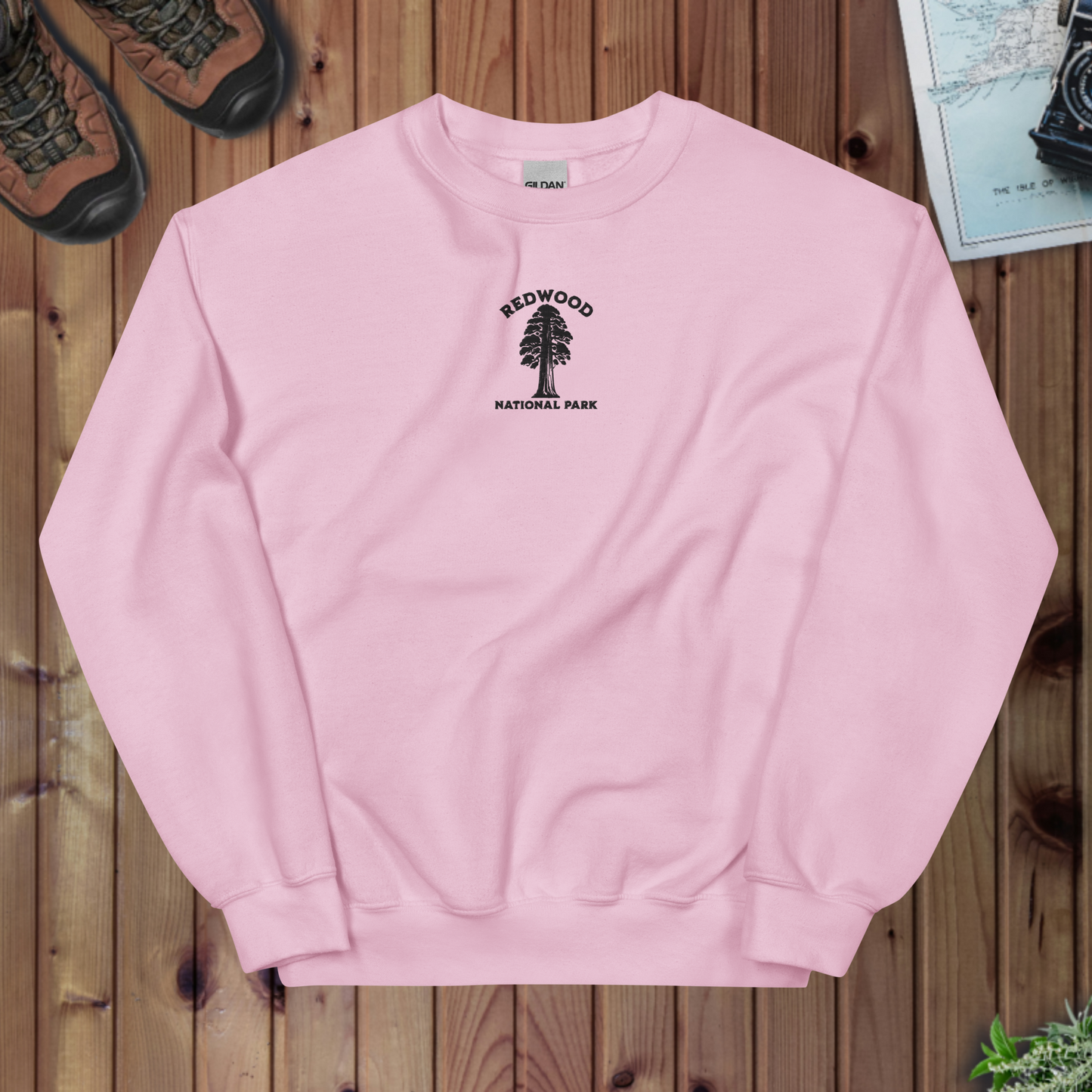 Pink sweatshirt with Redwood National Park logo on a wooden surface